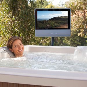 A woman relaxing in a hot tub, with a HotSpring Monitor.