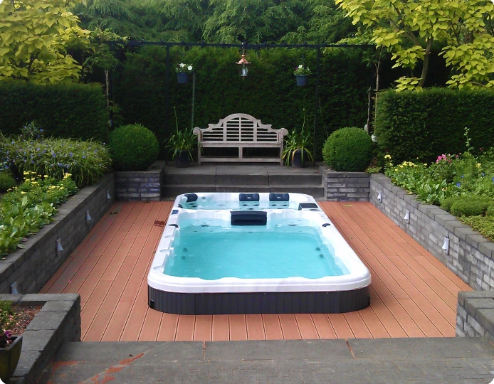 A cozy hot tub on a wooden deck under the open sky, surrounded by greenery and natural scenery.