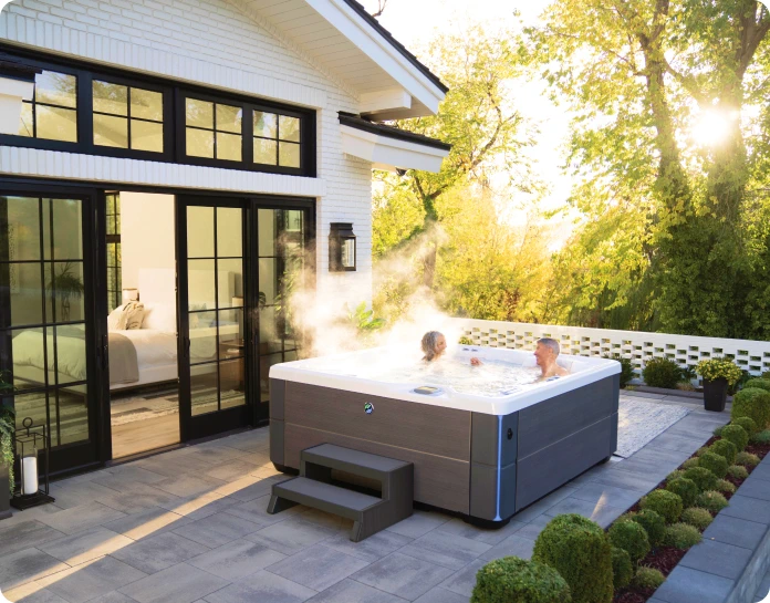 An older couple sitting in a hot tub on the terrace, surrounded by nature.