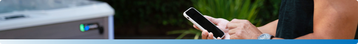 A person stands next to a hot tub, holding a smartphone.